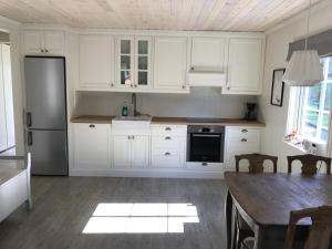 克维内斯达尔Guse gård的厨房配有白色橱柜、桌子和冰箱。