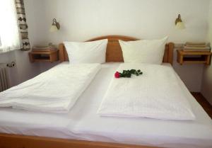 法尔先特Farchant-Zugspitze的一张铺有白色床单的床,上面有花