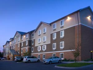 路易斯威尔WoodSpring Suites Louisville Jeffersontown的一座大型砖砌建筑,停车场内有车辆停放