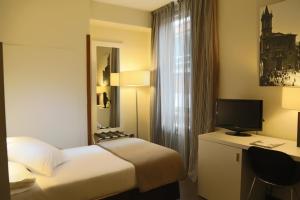 奥维多Gran Hotel España的酒店客房配有一张床和一张书桌及一台电视