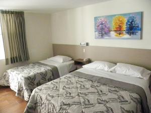 塔克纳Nice Inn Tacna的酒店客房设有两张床,墙上挂有绘画作品