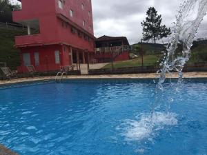 圣巴巴拉Pousada Maria Francisca的红色建筑前的游泳池中的喷泉