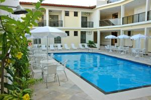 阿拉卡茹圣曼努埃尔普拉亚酒店的酒店旁的游泳池配有椅子和遮阳伞