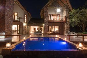 侯斯普瑞特eKhaya Bush Villa的夜间在房子前面的游泳池