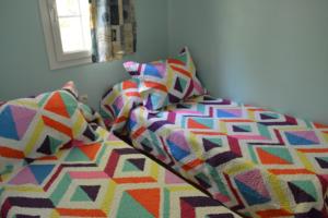 代穆斯冒险海滩露营地的一张带色彩缤纷的被子和枕头的床