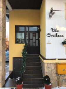 弗尔尼亚奇卡矿泉镇斯维特拉娜旅馆的黄色的建筑,有黑色的门和楼梯