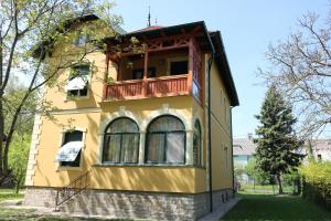 凯斯特海伊Anna Villa的黄色房子的顶部设有阳台