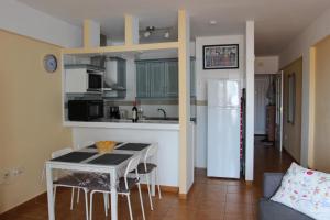圣地亚哥港Ocean View Apartment at the beach Playa de La Arena的厨房配有桌子和白色冰箱。
