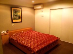 大阪马加达酒店（仅限成人）的一间卧室配有一张红色棉被的床