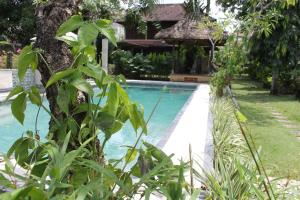 沙努尔普里库塔莱斯塔里旅馆的一座种植了植物的院子旁的游泳池