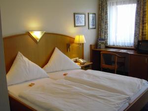 巴特诺因阿尔-阿尔韦勒霍亨索伦酒店的一间卧室配有一张带白色床单的床和一张书桌。