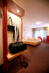 WilgartswiesenHotel Am Hirschhorn - Wellness - Spa - and more的酒店客房,带一张床和行李箱