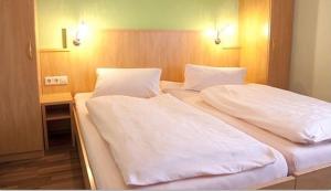 阿尔腾斯塔特贝格尔斯图本餐厅酒店的一间卧室配有两张带白色床单的床和一张书桌