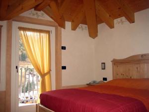 泰穆Garni La Genziana的一间卧室设有红色的床和窗户。