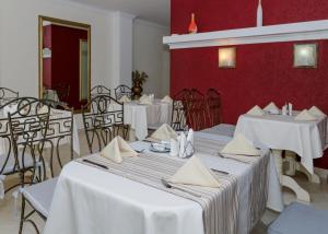 敖德萨勒尔蒙托夫斯基酒店的一间设有白色桌椅和红色墙壁的餐厅