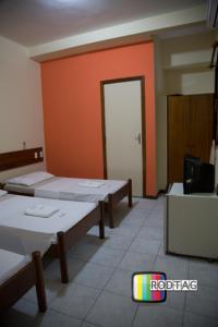 萨尔瓦多Hotel Porto Da Barra的一间设有三张床和橙色墙壁的房间
