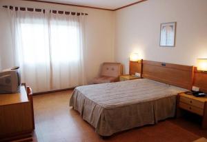 普拉多博玛苏克索酒店的一间卧室配有一张大床和一把椅子