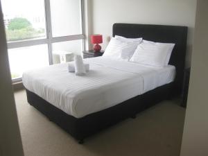 布里斯班菲尔多普公寓的卧室配有一张带白色床单的大床和窗户。
