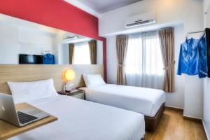 雅加达Monoloog Hotel Pasar Baru的酒店客房设有两张床和一张书桌上的笔记本电脑