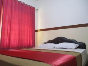 雅加达图古阿斯里酒店的一间卧室配有一张带红色窗帘的床