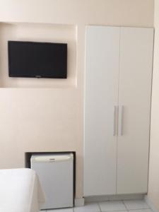 马塞约Hotel Porto Grande的卧室配有白色橱柜和平面电视。