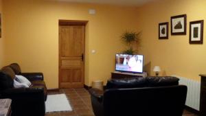 Fuentes de OñoroEl Condado Casa Rural的客厅配有两张真皮沙发和一台电视机