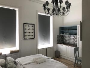 布达佩斯班伦斯格林杜尔7号公寓式酒店的一间卧室配有一张床、两个窗户和吊灯