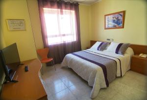 圣地亚哥德拉里贝拉马德里酒店的一间卧室配有一张床、一张书桌和一台电视