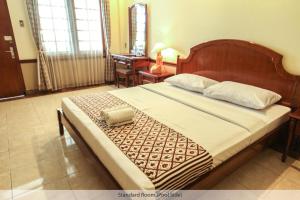 日惹都塔宾馆的一间卧室配有一张大床和木制床头板
