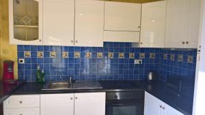 阿布维尔Baie de Somme Abbeville Appart的厨房配有白色橱柜、水槽和蓝色瓷砖