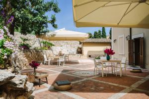 锡拉库扎阿基米德旅馆的一个带桌椅和遮阳伞的庭院