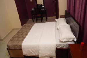 坎帕拉Diamonds Hotel Kampala的卧室内的一张大床,配有桌子
