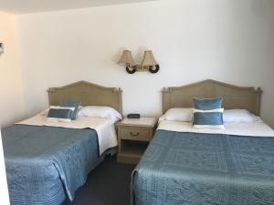 五月岬郡Cape Harbor Motor Inn的一间卧室设有两张床,墙上配有一盏灯。