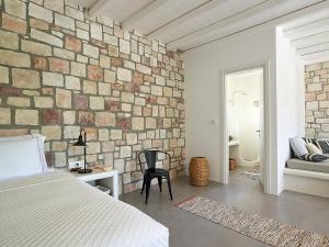 TriovasálosStudio Vipera的卧室设有砖墙、一张床和一把椅子