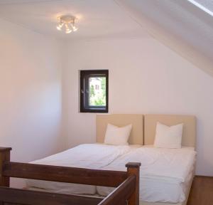 巴拉顿菲赖德Ékes Vendégház的一间卧室配有一张带白色床单的床和一扇窗户。