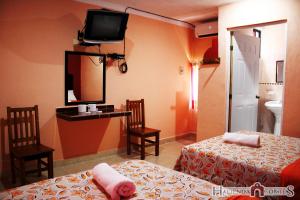 梅里达Hotel Hacienda Cortes的酒店客房设有两张床和一台墙上的电视。