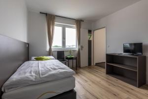 根瑟恩多夫Wein4tler-Motel的一间卧室设有一张床、一台电视和一个窗口。
