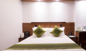孟买翠布橄榄旅馆的卧室配有带绿色枕头的大型白色床