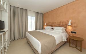 卡拉马孔Bitzaro Grande Hotel & Suites的一间卧室配有一张大床和电视
