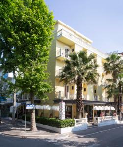 里乔内Hotel La Nidiola的一座黄色的大建筑,前面有棕榈树