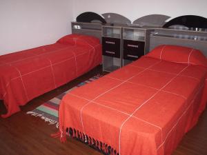 Resende CostaPousada Canto da Maritaca的一间卧室配有两张红色床罩和一张桌子