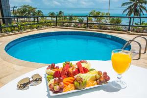 福塔莱萨金色福塔莱萨因特城市酒店的游泳池畔的桌子上放着一盘水果和果汁