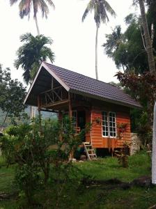 ManinjauEka's Bungalows的一座带门廊和棕榈树的小木房子