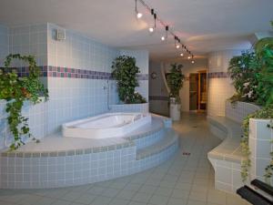 多比亚科托布拉彻霍夫酒店的蓝色瓷砖浴室设有浴缸和植物