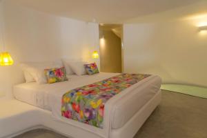 易莫洛林圣托里尼阿尤巴公寓的白色卧室配有一张带彩色毯子的床