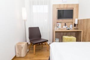 乌尔姆高登尼斯拉得酒店的一间卧室配有一张床、一把椅子和电视
