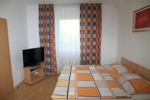 林茨Appartementhaus Anna的一间卧室设有四张床、电视和窗帘