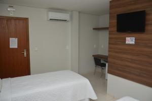 Novo ProgressoTapajos Palace Hotel的一间卧室配有一张床,墙上配有电视