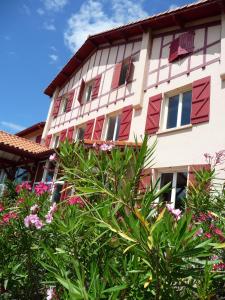 塔尔诺斯Village Vacances La Forêt des Landes的一座建筑前方有红色窗户和鲜花