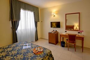 圣乔瓦尼·罗通多Hotel Centro di Spiritualità Padre Pio的酒店客房带一张床、一张书桌和一面镜子